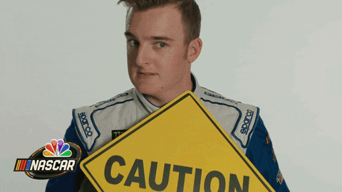 Race car driver holding a triangle caution sign