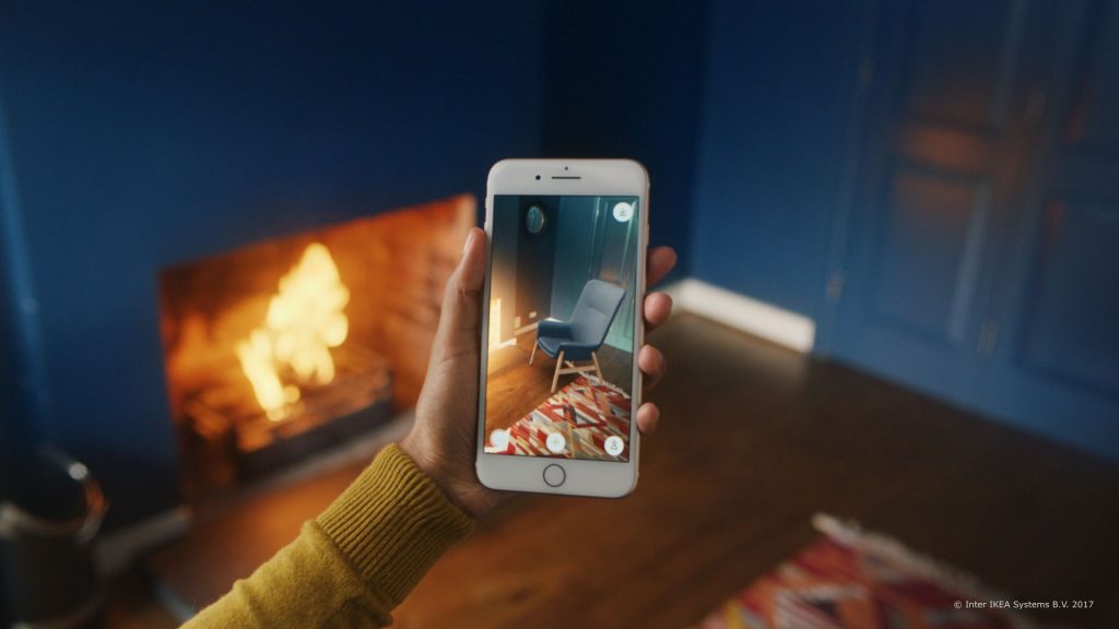 Hand holding a phone displaying a room background, suitable for a VR presentation on a website